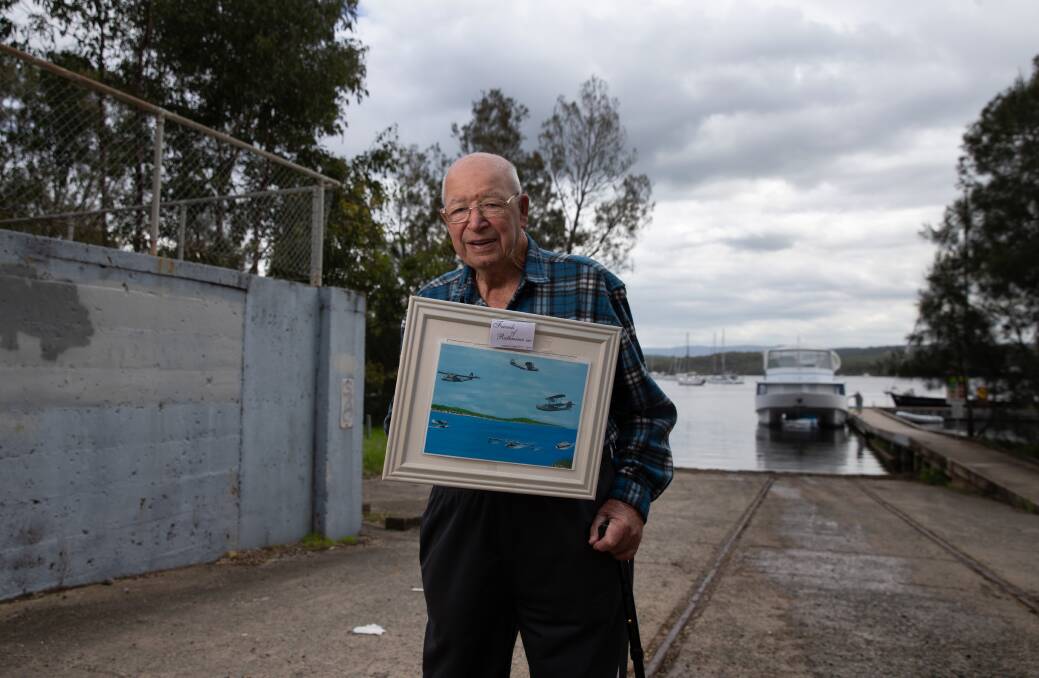 Jack Carter at the former RAAF base at Rathmines with a copy of one of his paintings, depicting Catalinas in action. Picture: Marina Neil
