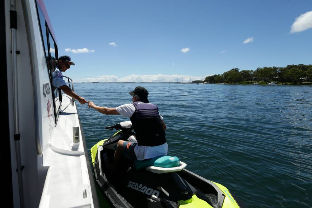 INSPECTION: Boating safety officer Chris Austen checks the licence of Mitchell Snowden in Wangi Bay.