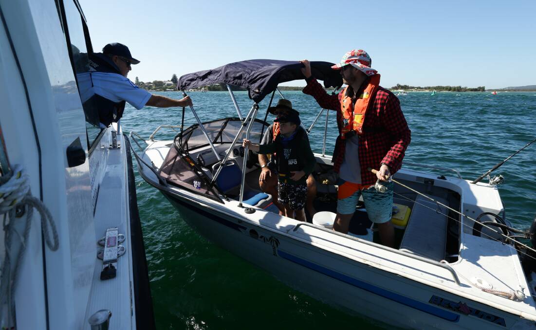 SAFETY FIRST: NSW Maritime officer Peter Browne talks with members of the Archer family near Swansea Channel, as they head out on the lake in their boat for the first time in months. Pictures: Jonathan Carroll 