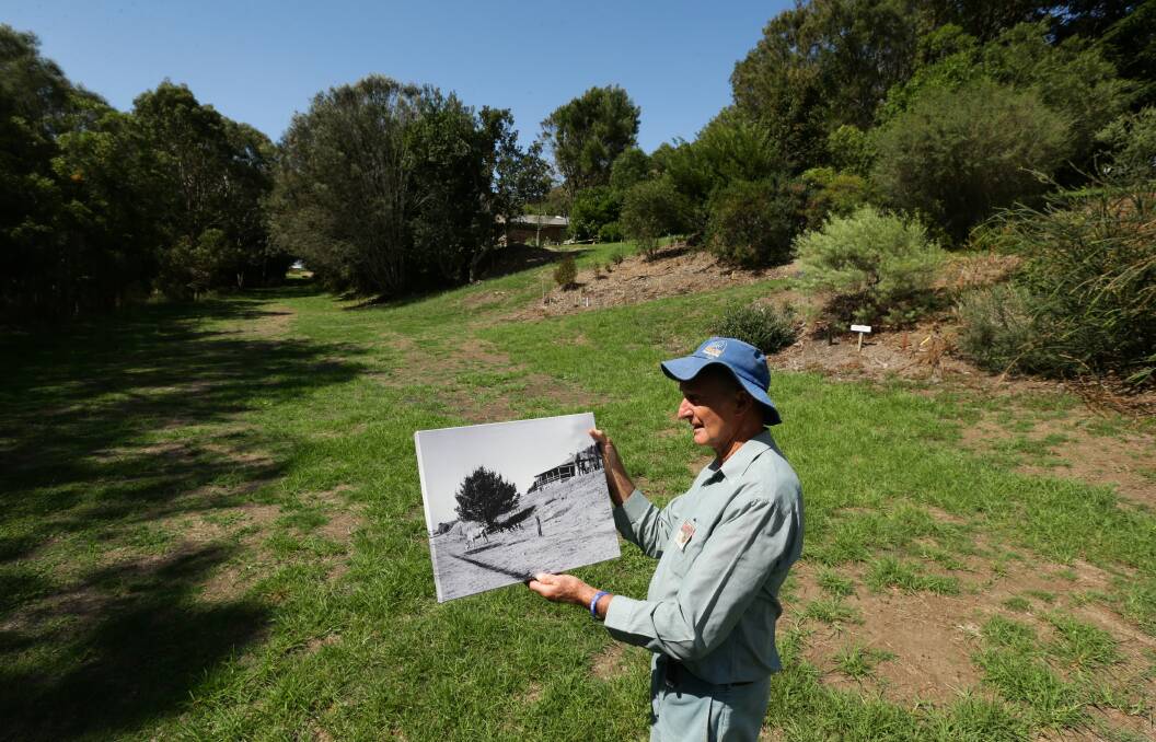 John Le Messurier holds a photo showing how the Glenrock Scout Camp looked before he began creating the gardens. Picture: Jonathan Carroll