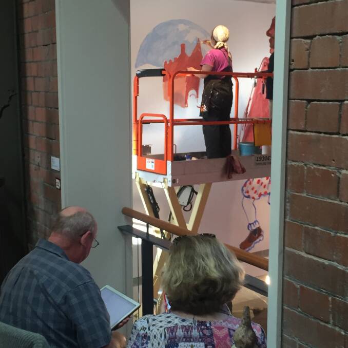 Wendy Sharpe paints the gallery building on the gallery's wall, as spectators watch on. Picture: Scott Bevan