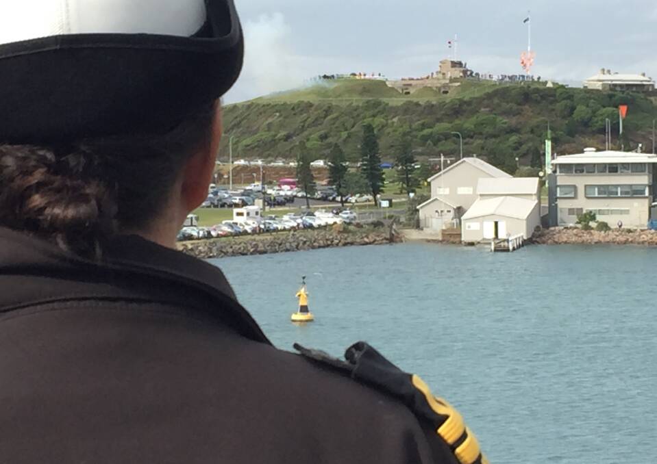 SALUTE: An officer on HMAS Newcastle watches the Fort Scratchley gun fire as a gesture of farewell. 