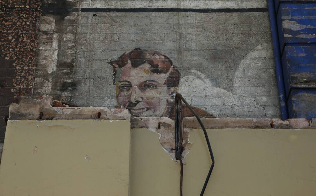 A face from the past emerges on a wall neighbouring the Hunter Street demolition project. Picture: Simone De Peak