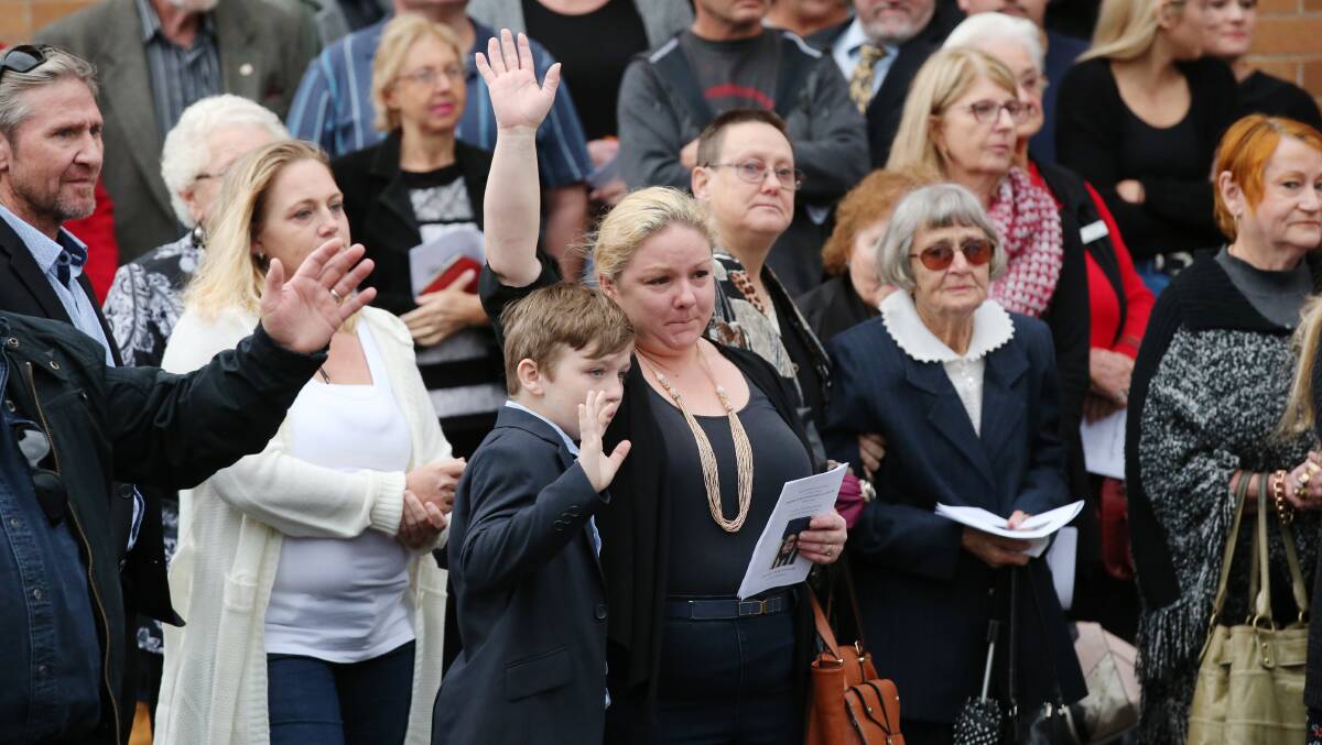 FAREWELL: Jenny Allen (centre) joins family, friends and strangers in waving goodbye to her older brother, Bernie Sessions, at his funeral held at Shortland. Picture: Max Mason-Hubers  