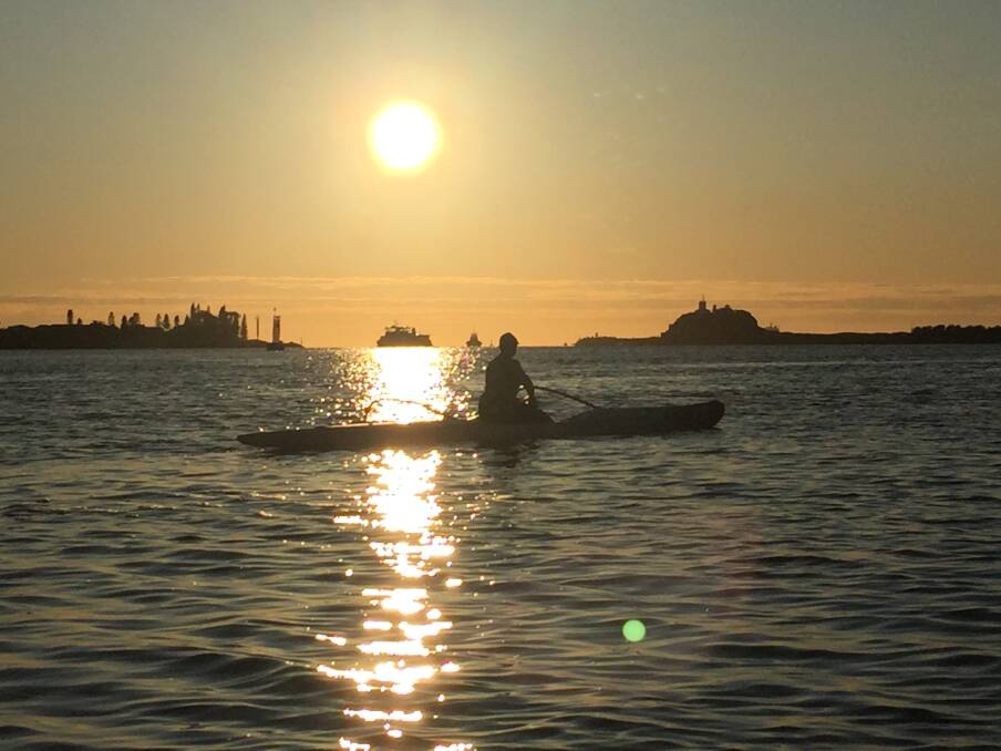Outrigger canoe paddler Alaine Morris greets the day on Newcastle harbour. Picture: Scott Bevan 