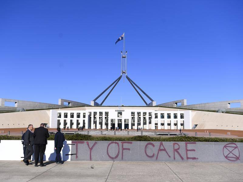 Workers cover graffiti after an Extinction Rebellion protest outside Parliament House.