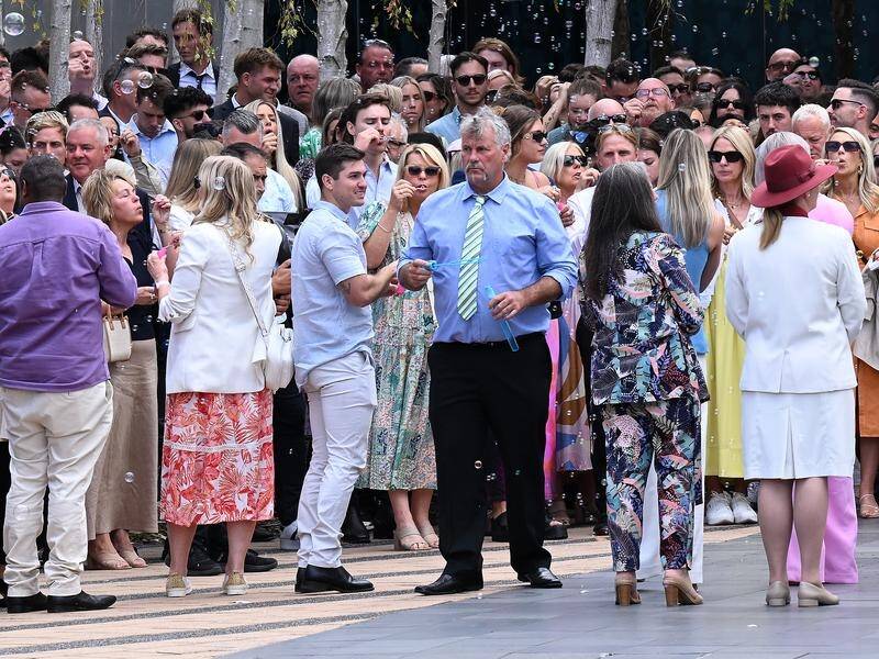Gary Baird surrounded by mourners at a memorial service for his son, TV presenter Jesse Baird. (James Ross/AAP PHOTOS)