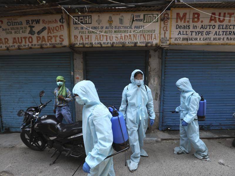 Heath workers spray disinfectant near shops in New Delhi. India's virus death toll is past 100,000.