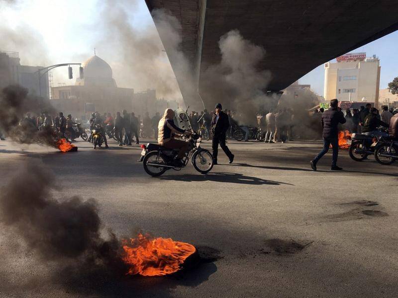 Iranians protesting against a fuel price rise have blocked roads and clashed with security forces.