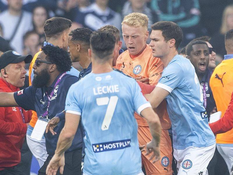 A bleeding Tom Glover, Melbourne City's keeper, is escorted to safety after the pitch invasion. (Will Murray/AAP PHOTOS)
