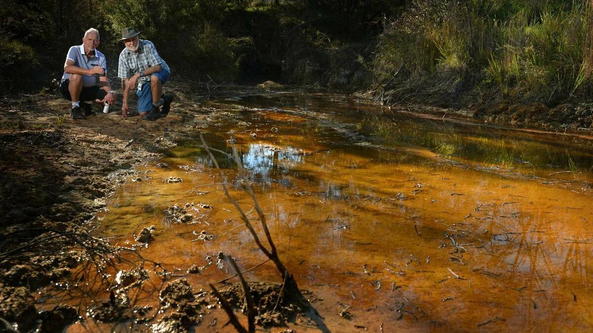 Phil Fiveash and Col Maybury, of Kurri Kurri Landcare, at the creek polluted by old mine workings. Picture: Marina Neil