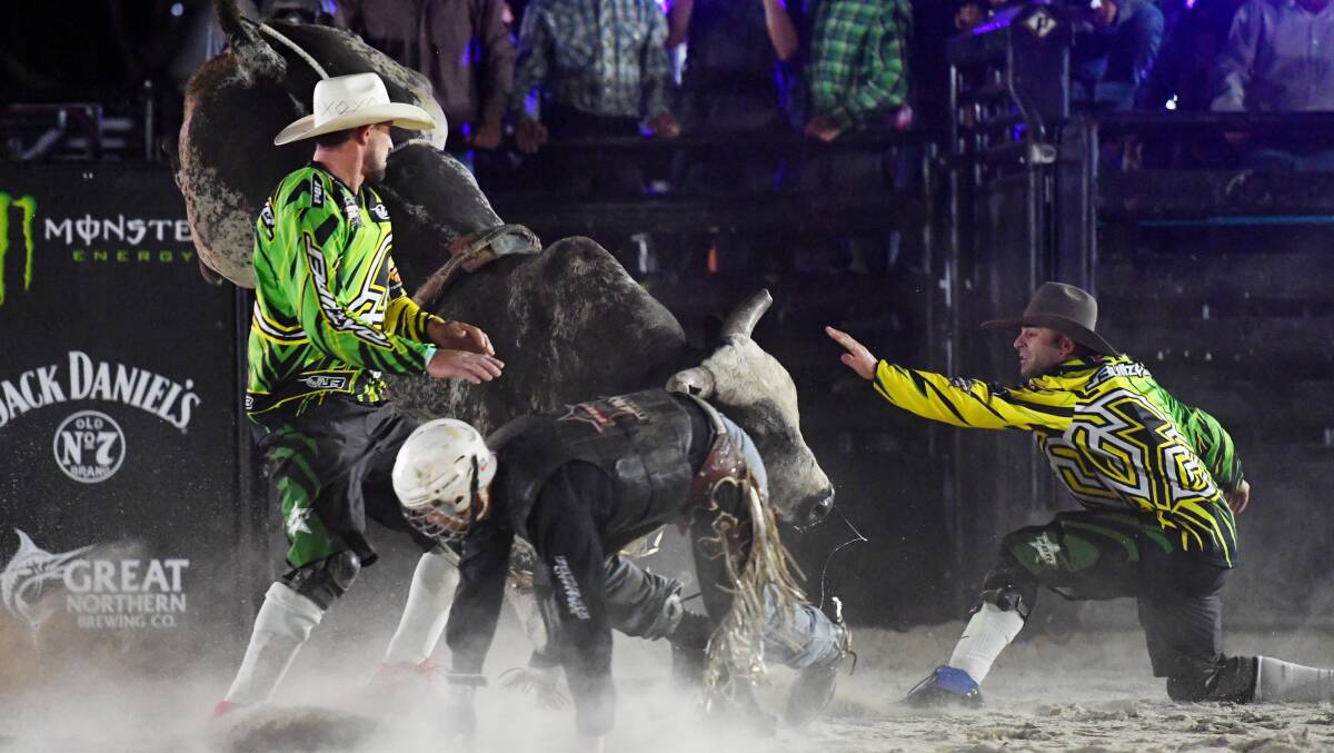 DEFENCE: Protection Athletes Mitch Russell and Geoff Hall guard a fallen rider after he's come unseated at one of the many Professional Bull Riding Invitationals held around the country. Picture: PBR Australia