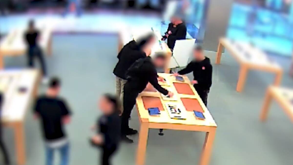Three men bundle up display smart watches at the Apple Store.