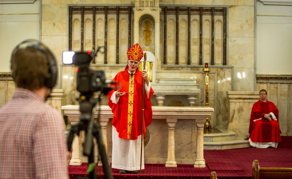 Roll camera: Catholic Bishop Bill Wright conducts the Good Friday service in the empty cathedral. Picture: Marina Neil