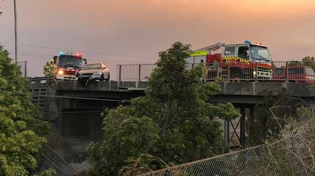 The car hangs over the ledge of the railway overpass at Teralba on Monday evening. Picture: Emma Dunn