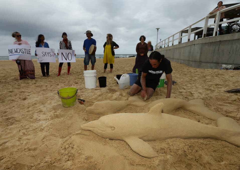 Queensland artist Dennis Massoud spent Tuesday afternoon making dolphin sand sculptures on Nobby's Beach to protest against seismic testing off the coast of Newcastle. Pictures: Jonathan Carroll