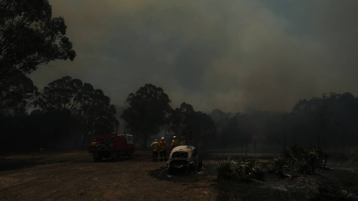 Up in smoke: Firefighters survey the scene at Greta during a bushfire late last year. Picture: Simone De Peak