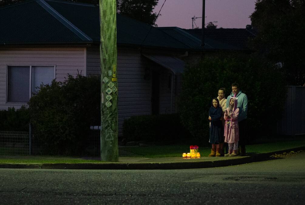 A family joins the tribute in Ada Street, Waratah, on Anzac Day, 2020. Picture: Max Mason-Hubers