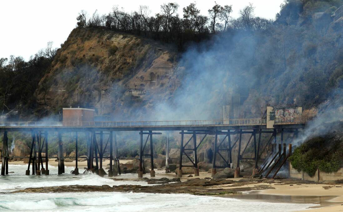 Smouldering: The Catherine Hill Bay jetty after a major bushfire swept through the area in 2013. Picture: Simone De Peak
