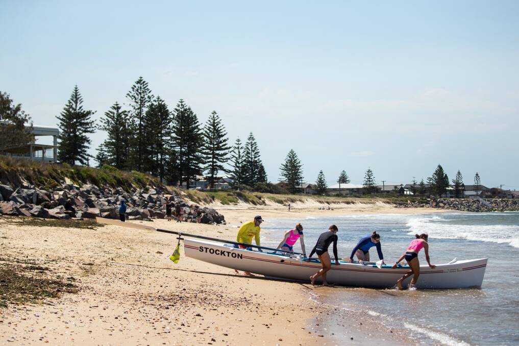 CRISIS: A boat crew heads out from a strip of sand at Stockton beach on Sunday. Picture: Marina Neil 