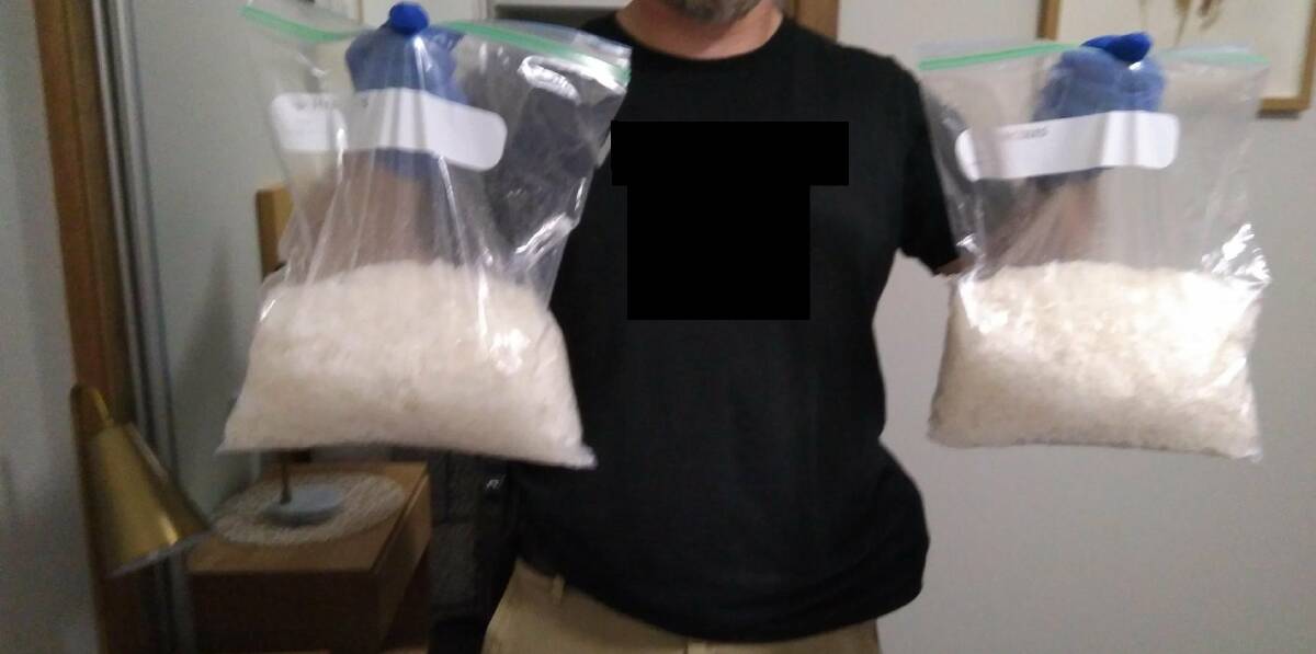 RAID: A police officer holds up two bags of a substance alleged to be methylamphetamine after the bust at Shortland on Friday. Picture: NSW Police 
