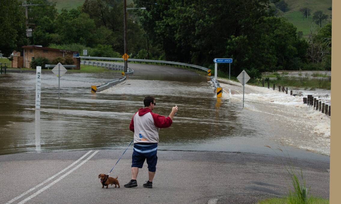 YOU CAN LEAD A DOG TO WATER: A man and his dog on a flooded Stroud Hill Road in Dungog. Picture: Marina Neil