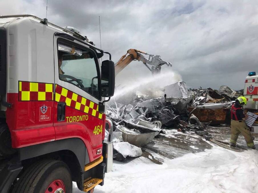 JOINT EFFORT: A 30-tonne excavator assisted firefighters with a blaze at a recycling plant at Teralba. Picture: Fire and Rescue NSW