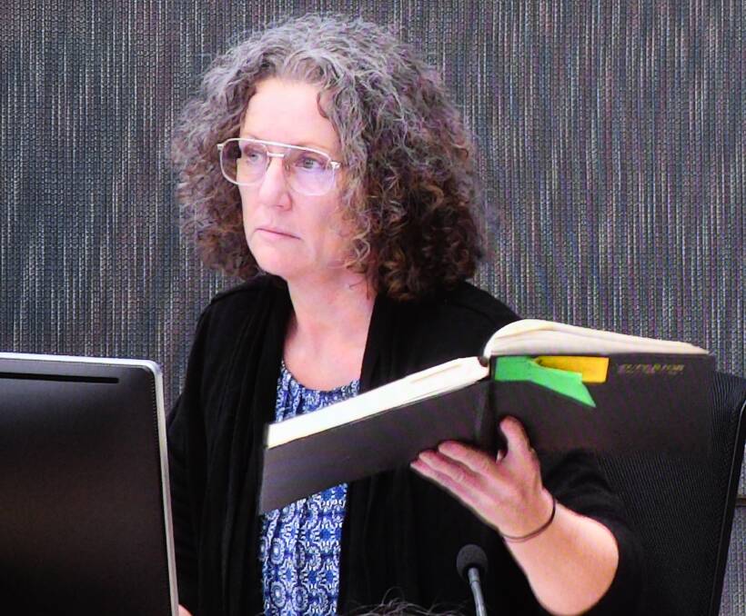 Kathleen Folbigg holds one of her original diaries whilst appearing via video link at the NSW Coroners Court in 2019.