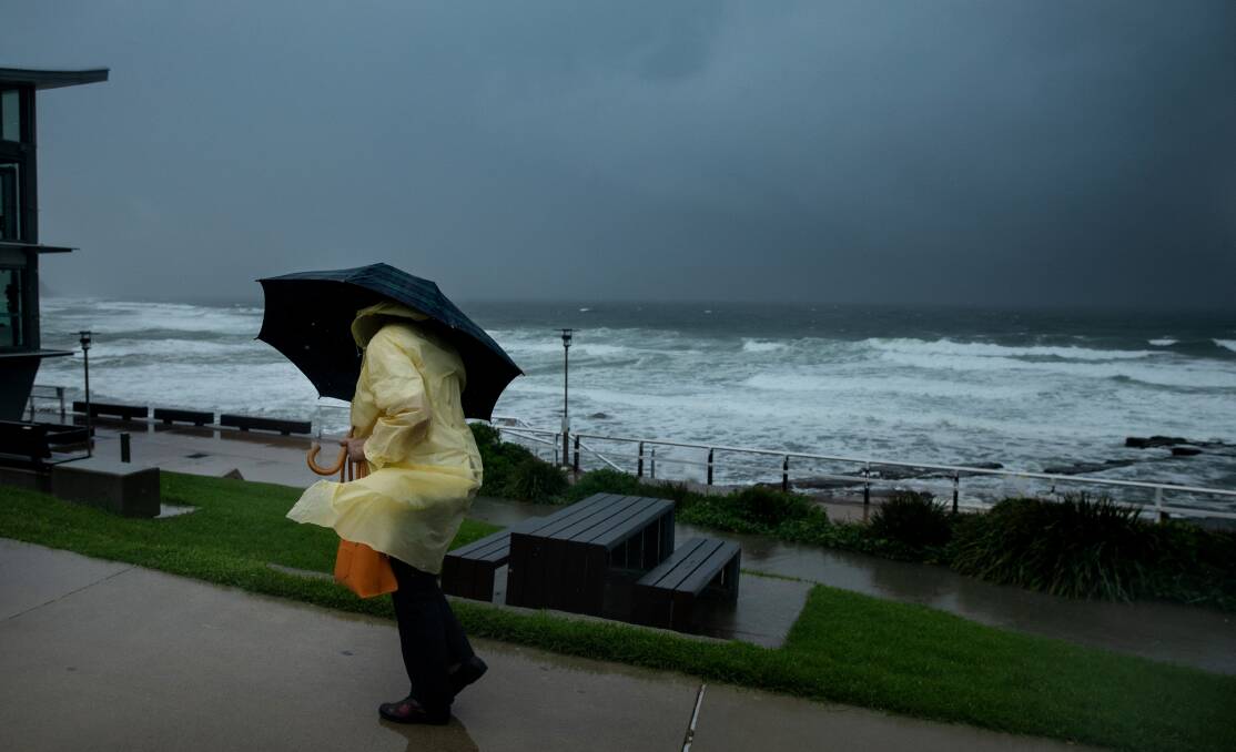 BLOWING A GALE: A woman battles to hold her umbrella at Merewether during a wet March. Picture: Marina Neil