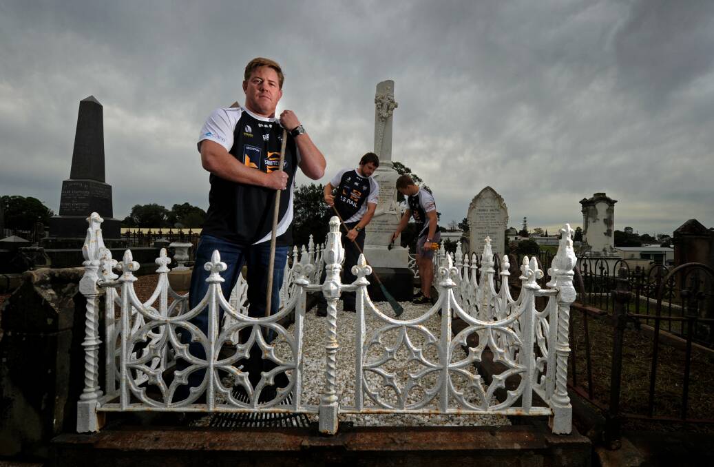 PAYING RESPECTS: Maitland Rugby Club vice-president Ben Emmett and players Rhys Lloyd and James Johnston clean up Robert Seddon's grave.