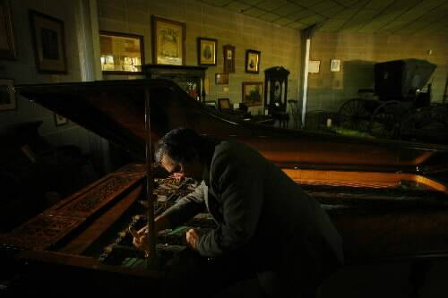 KEY MUSIC: Michael Burns cleans an antique piano. –  Picture by Peter Stoop