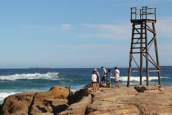 CLOSE EYE: Members of the public scan the surf  near the old Redhead beach shark tower. –  Picture by Ryan Osland