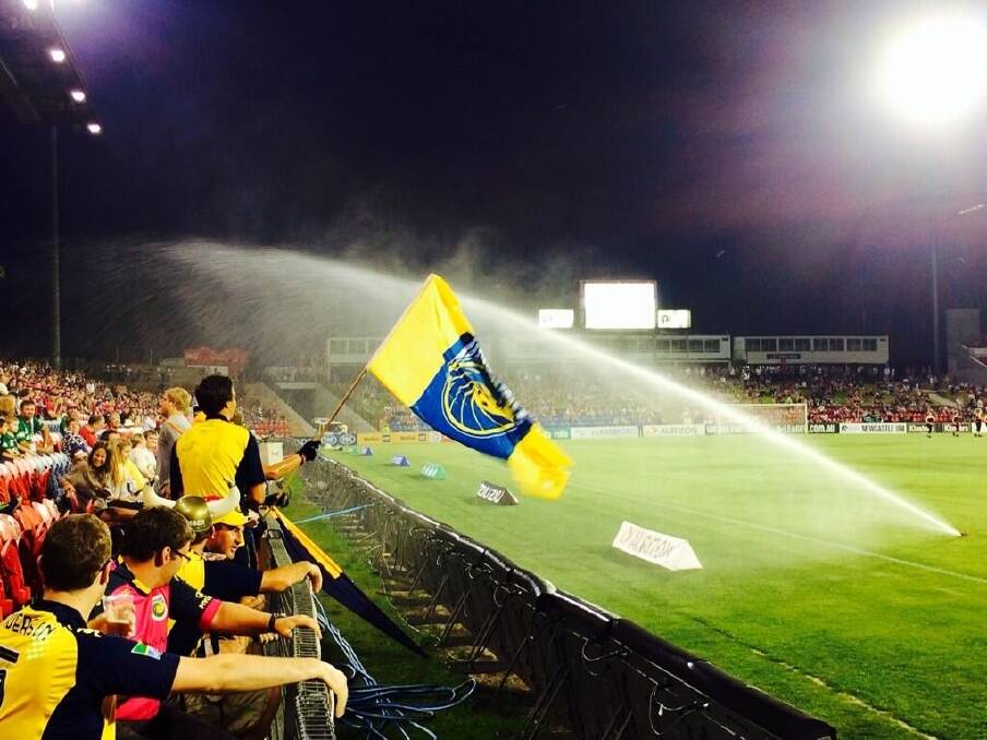 Central Coast Mariners fans are hit by a sprinkler at Hunter Stadium.