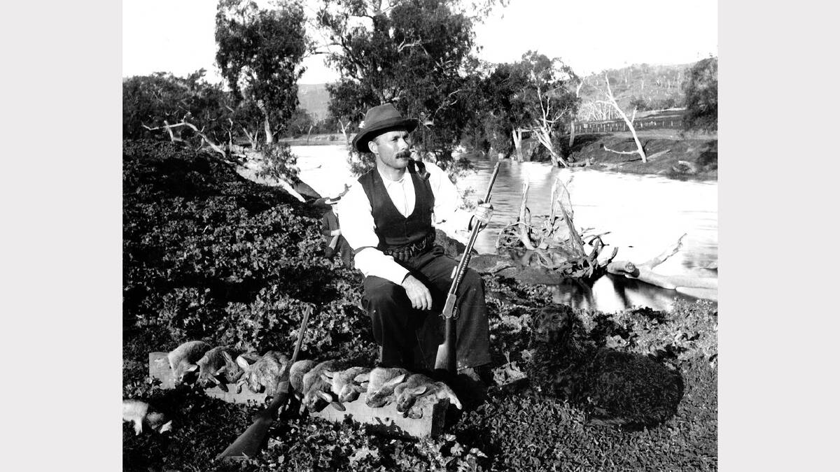 ARCHIVAL REVIVAL 1900s: Photographs from the Newcastle Herald's files.unidentified man with rabbit belts and black dog and gun sitting near creek. Believed to be at Gundy. 