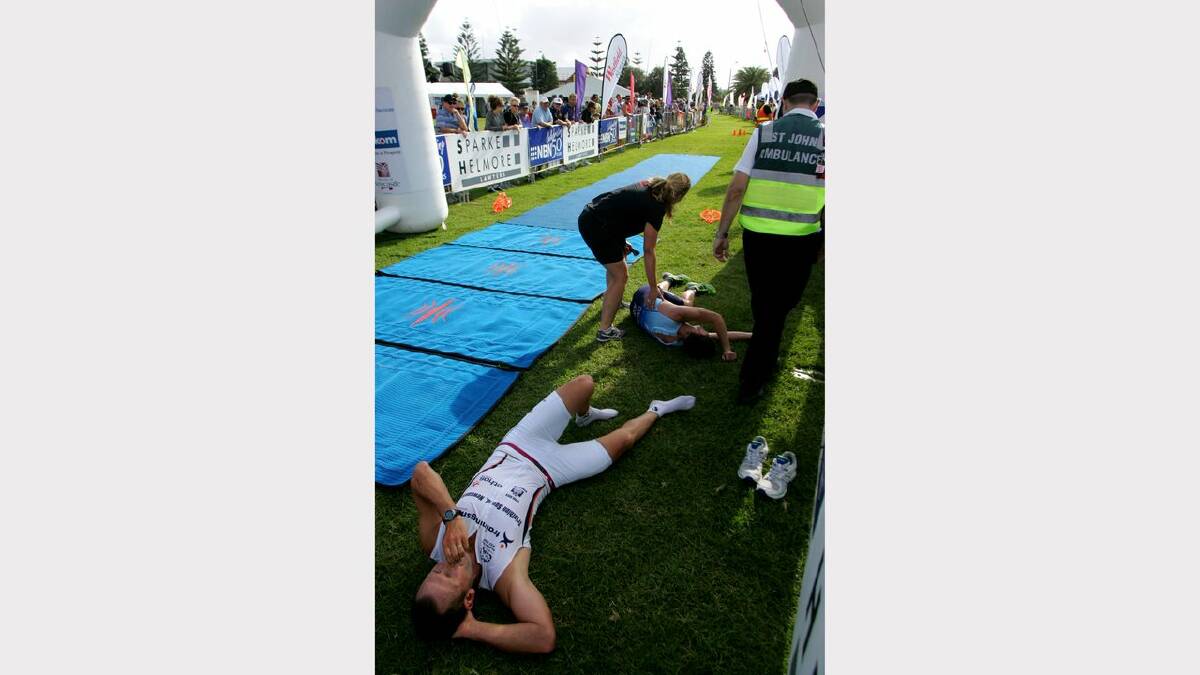 ENERGY: Action from the Sparke Helmore NBN Triathlon in Newcastle on Sunday.  2nd place finisher Tim Lang (closest) on the ground after suffering a cramp and 3rd place finisher Elliott Collins suffering exhaustion at the finish line of the race. Picture Max Mason Hubers.