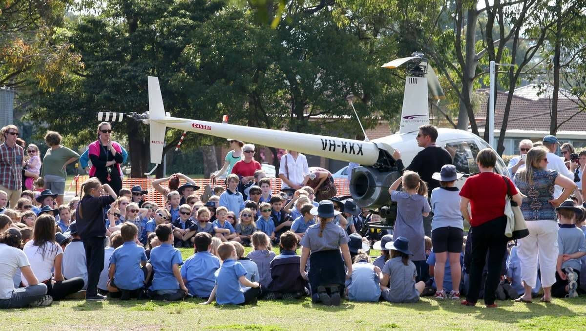 Super dad and helicopter pilot Dwayne Sharrock at Eleebana Public School, where his kids  Riley, Ethan and Jenna are students. Mr Sharrock flew the helicopter to school as part of a lesson on careers - and big and small machines. Picture Dean Osland.