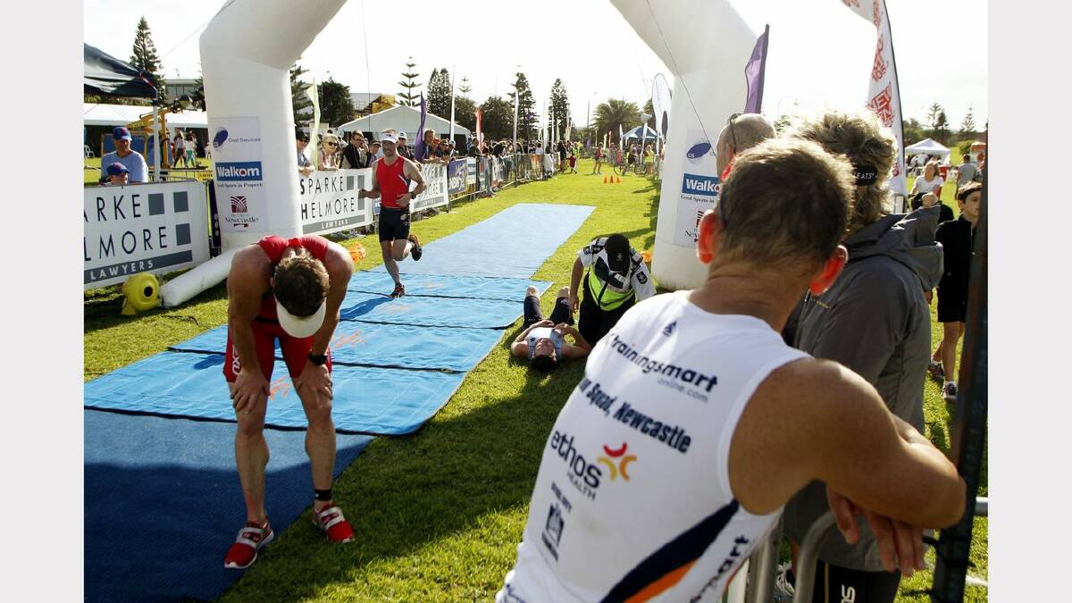 ENERGY: Action from the Sparke Helmore NBN Triathlon in Newcastle on Sunday. Olympic Distance Triathlon runner up Tim Lang (R) watching as a paramedic attends to Elliott Collins (centre) who was indisposed after crossing the line in third place. Picture Max Mason Hubers.