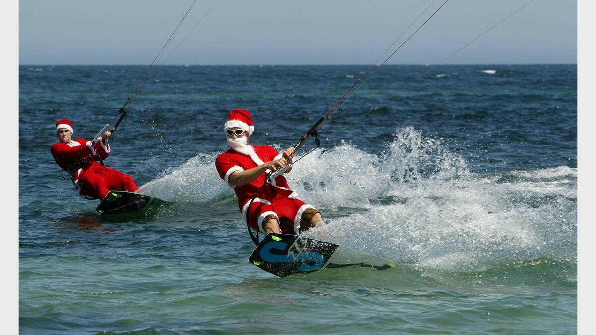 Kite-surfing Santas at Nobbys Beach, Newcastle. James Vandervoort, left, and Franz Riembauer, right.  Picture Jonathan Carroll. 