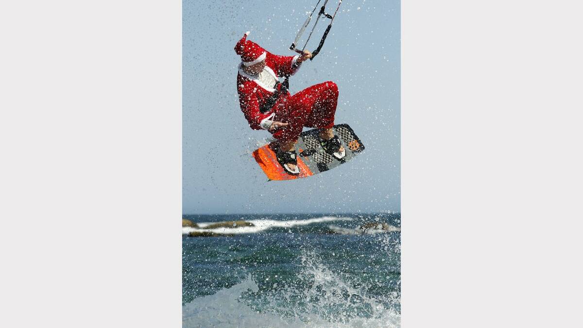 Kite-surfing Santas at Nobbys Beach, Newcastle. James Vandervoort in action. Picture Jonathan Carroll. 