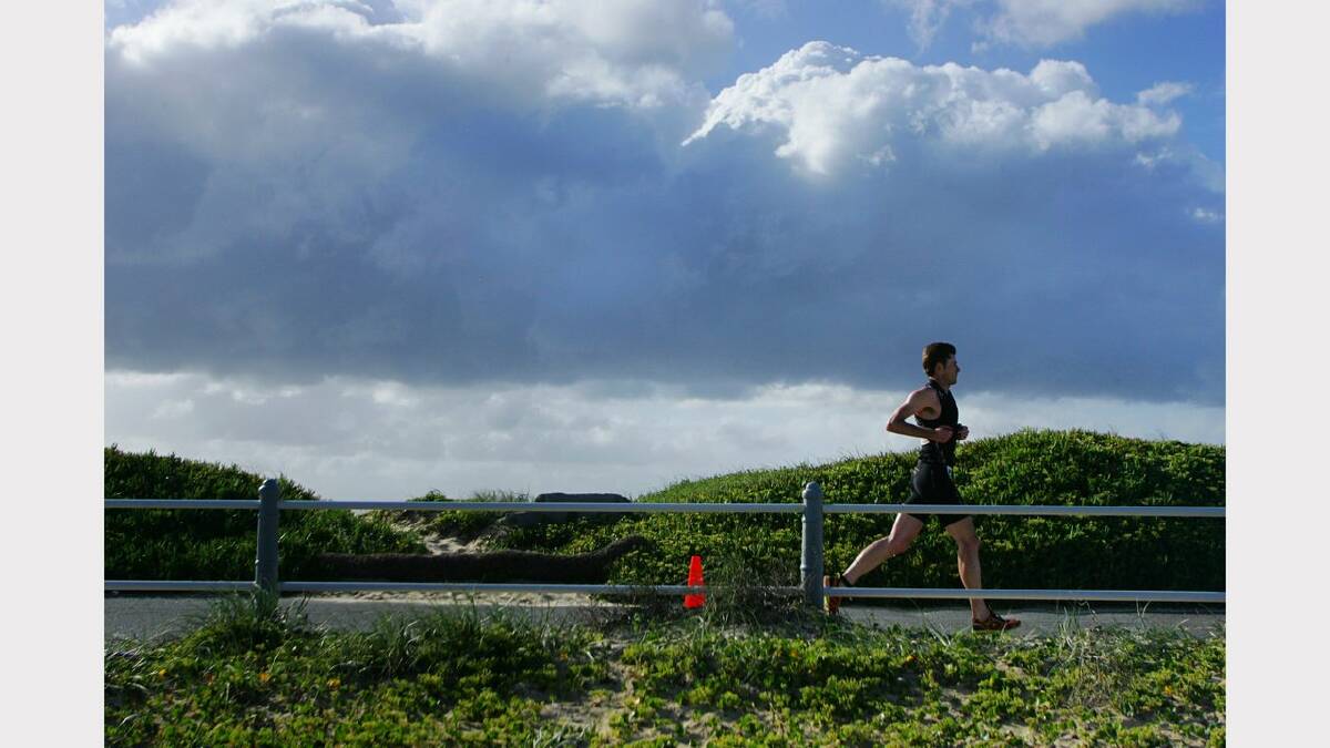 ENERGY: Action from the Sparke Helmore NBN Triathlon in Newcastle on Sunday. Stephen Ryan running on Nobbys breakwall during the Olympic Distance Triathlon race. Picture Max Mason Hubers.