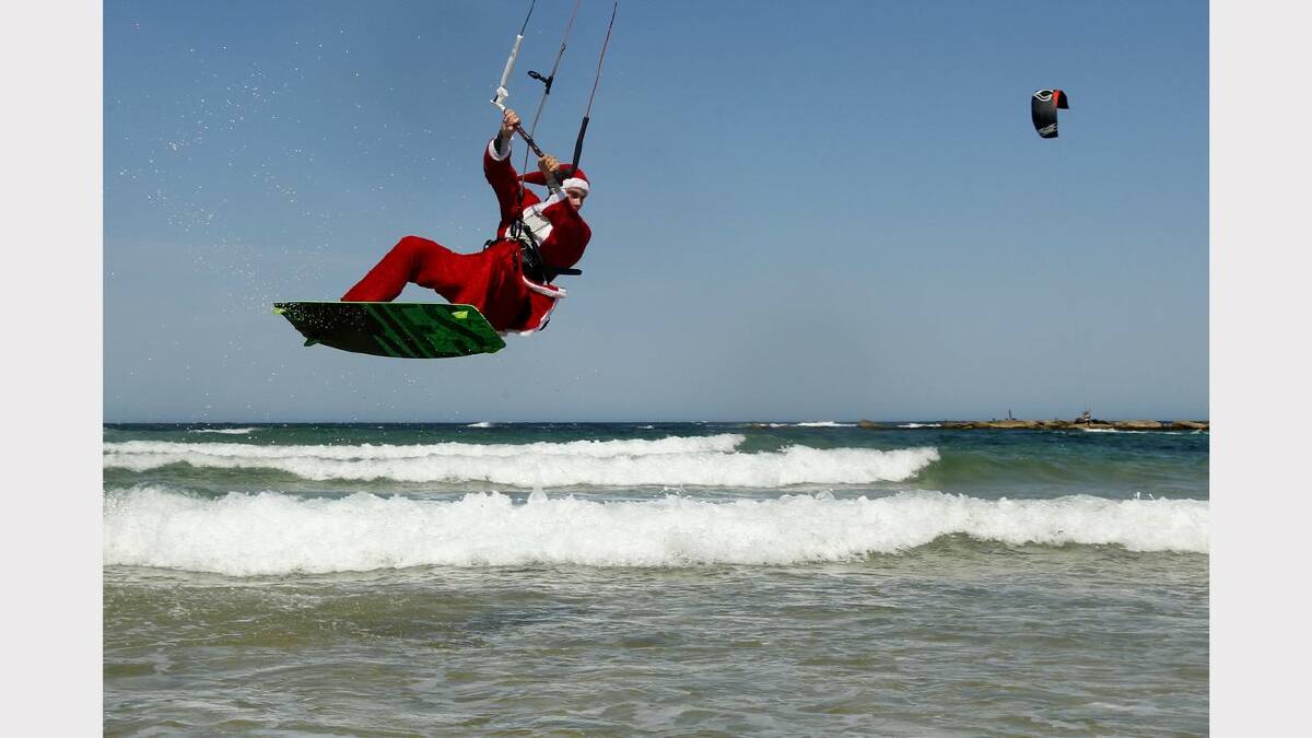 Kite-surfing Santas at Nobbys Beach, Newcastle. James Vandervoort in action. Picture Jonathan Carroll. 