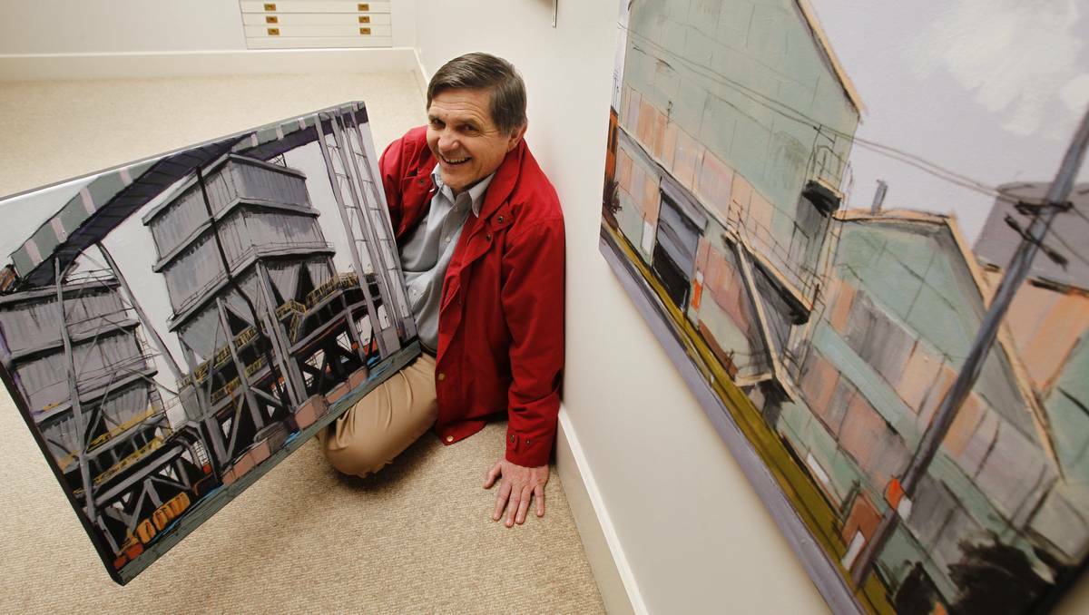 INDUSTRIAL ART: Mark Widdup, owner of Cooks Hill Galleries, with some of Christine Hundt's industrial landscapes currently showing at the gallery. Picture Max Mason Hubers