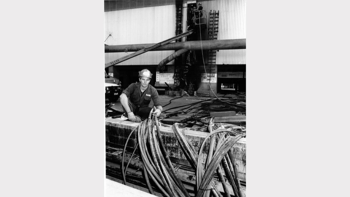 Peter Marshall works to repair electrical wiring that was damaged ofter a pot of molten aluminium broke open. Fire damage can be seen at back. Alcan aluminium smelter Kurri Kurri on  September 10, 1992. Picture: Eddie Cross  
