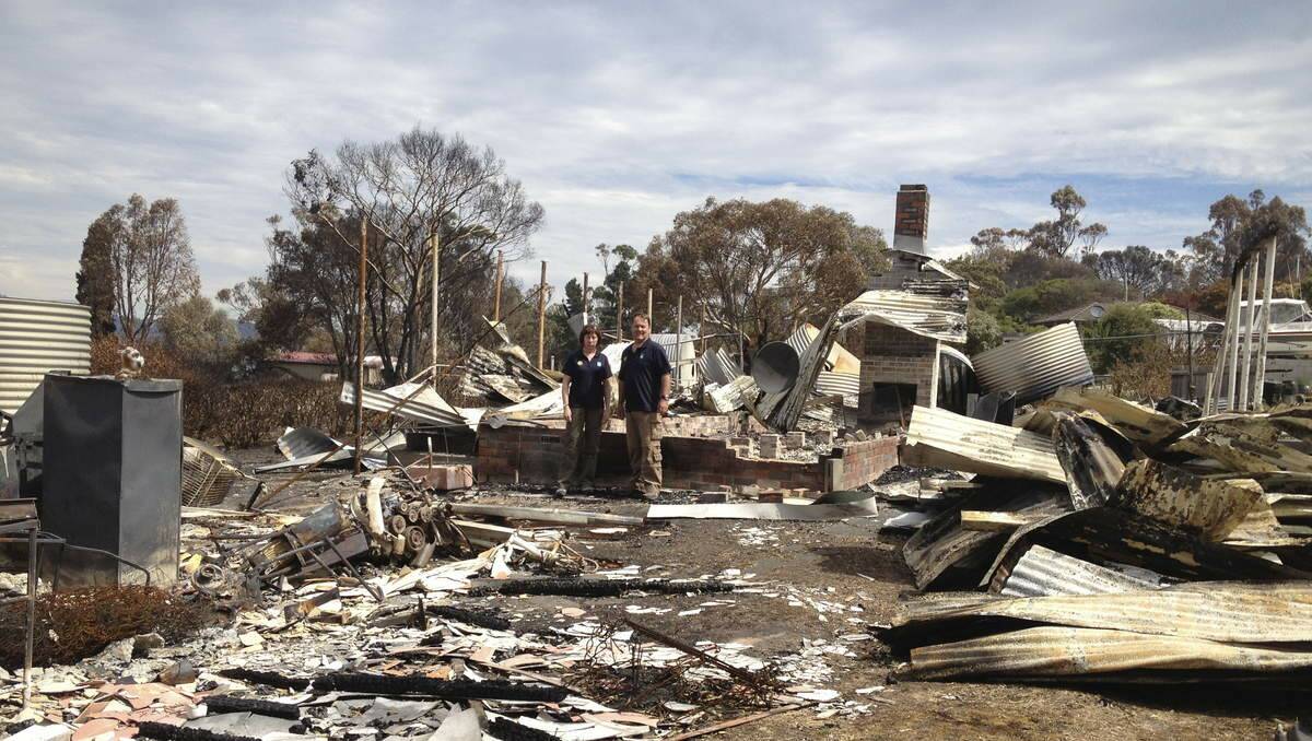 Rotarians Lynn and Scott Jarman stand and survey the ruins of a house in Dunalley, Tasmania.