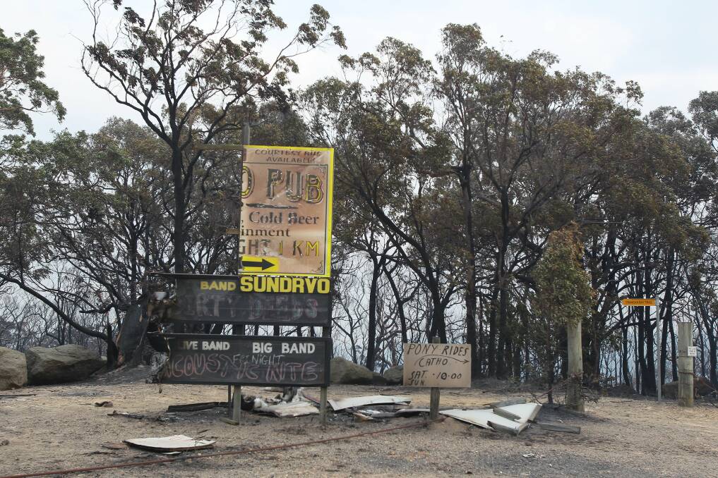 A scorched sign pointing to the Catherine Hill Bay pub. Picture: Peter Rae