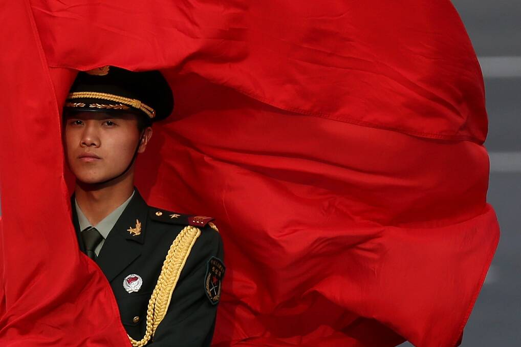 The wind blows a red flag onto the face of an honour guard before a welcome ceremony for Australia's Prime Minister Julia Gillard outside the Great Hall of the People in Beijing, China. Photo: Getty Images