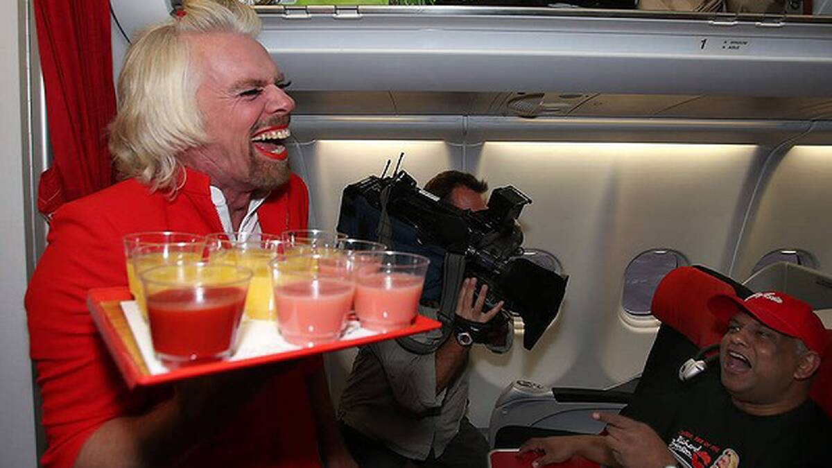 Sir Richard Branson serves drinks to Tony Fernandes prior to their flight to Kuala Lumpur at Perth International Airport. Photo: Paul Kane