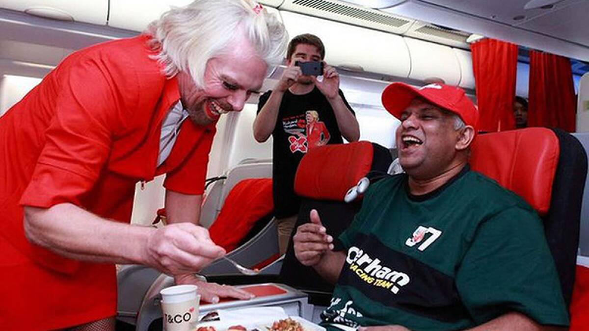AirAsia group chief Tony Fernandes being served by Richard Branson, who is dressed as a female flight attendant, in the air while flying from the Australian city of Perth to the Malaysian city of Kuala Lumpur. Photo: AirAsia